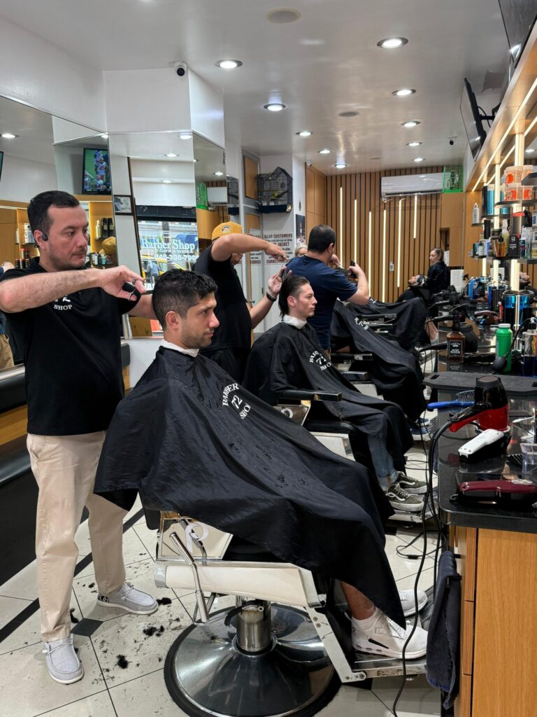 Barber giving a haircut to a seated client at Barbershop 72